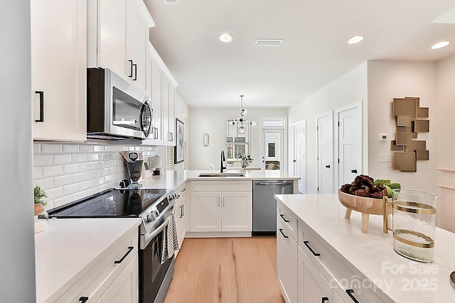 1223 E 16th St Unit 13, Charlotte, NC 28205 - kitchen featuring stainless steel appliances, light wood-style floors, light countertops, decorative backsplash, and white cabinets