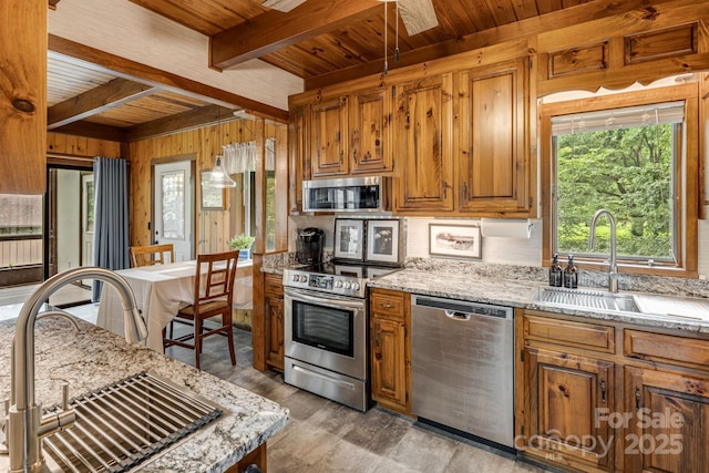 79 Creekside Ln, Spruce Pine, NC 28777 - kitchen featuring appliances with stainless steel finishes, a wood ceiling with exposed beams, wood walls, light wood-style flooring, and brown cabinetry