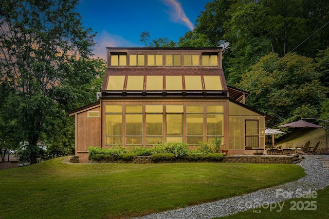 79 Creekside Ln, Spruce Pine, NC 28777 - back of house at dusk with a lawn and a sunroom