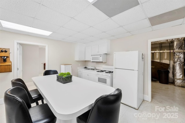 600 Queens Rd, Cherryville, NC 28021 - kitchen with white appliances, a paneled ceiling, white cabinetry, a breakfast bar area, and light countertops