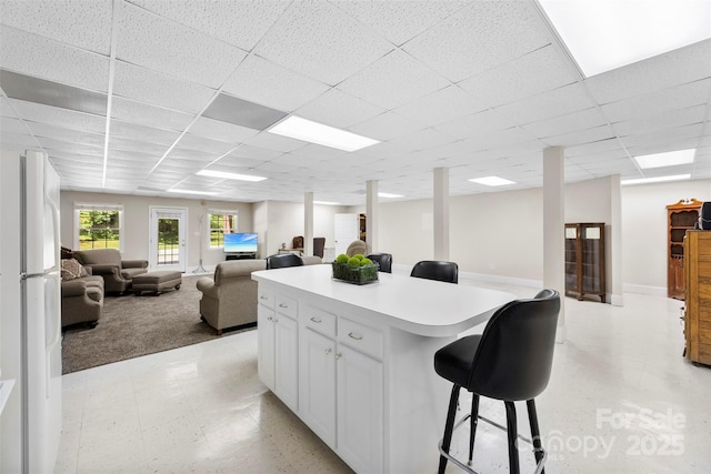 600 Queens Rd, Cherryville, NC 28021 - kitchen with a kitchen bar, open floor plan, a drop ceiling, white cabinetry, and light floors