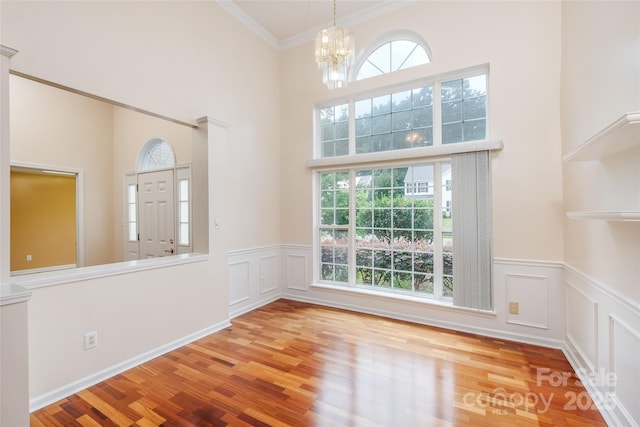 6414 Goldenblush Cir, Charlotte, NC 28269 - foyer entrance with a chandelier, wood finished floors, crown molding, a wainscoted wall, and a decorative wall