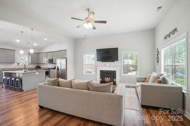 3256 Fairmead Dr, Concord, NC 28025 - living area featuring a ceiling fan, vaulted ceiling, dark wood finished floors, a glass covered fireplace, and recessed lighting
