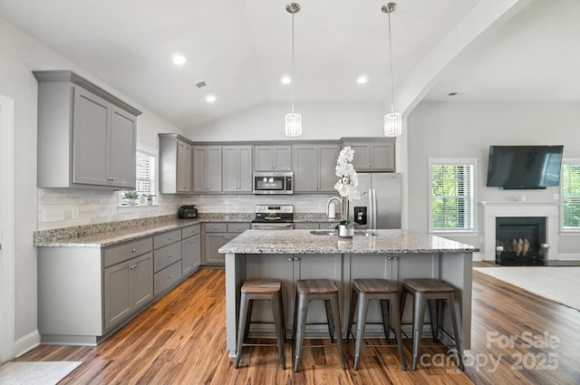 3256 Fairmead Dr, Concord, NC 28025 - kitchen with gray cabinetry, appliances with stainless steel finishes, a breakfast bar, tasteful backsplash, and lofted ceiling