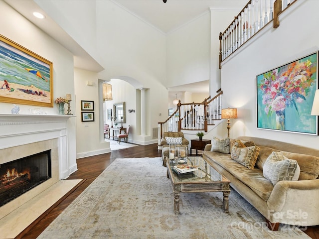 19205 Hidden Cove Ln, Cornelius, NC 28031 - living room featuring arched walkways, stairway, wood finished floors, a high end fireplace, and crown molding