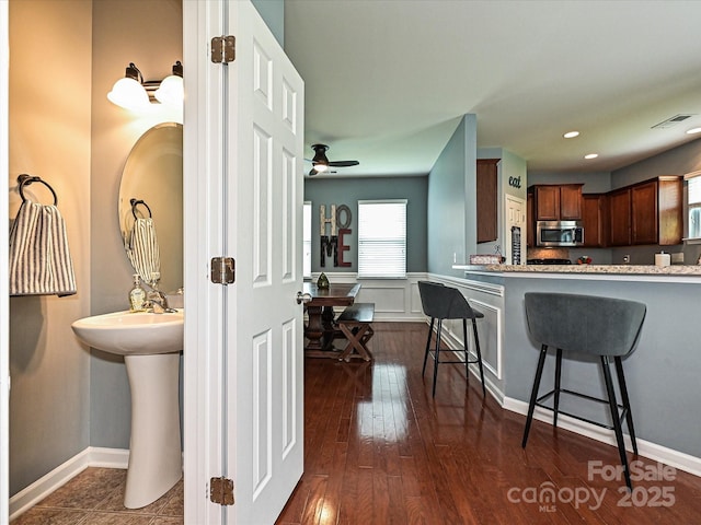 3009 Canopy Dr, Indian Trail, NC 28079 - kitchen featuring stainless steel microwave, a breakfast bar, dark wood-style floors, recessed lighting, and a ceiling fan