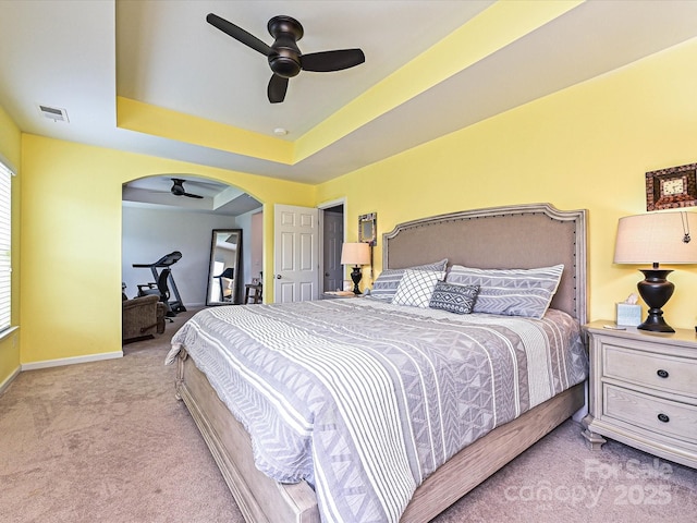 3009 Canopy Dr, Indian Trail, NC 28079 - bedroom featuring carpet flooring, arched walkways, a tray ceiling, and a ceiling fan