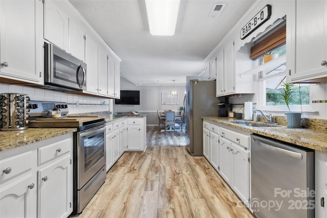 1507 Breckenwood Dr, Rock Hill, SC 29732 - kitchen featuring stainless steel appliances, white cabinets, light wood finished floors, decorative backsplash, and a peninsula