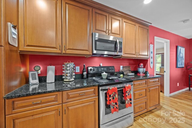 2369 Saratoga Run, Morganton, NC 28655 - kitchen with stainless steel appliances, light wood-style floors, brown cabinetry, and dark stone countertops