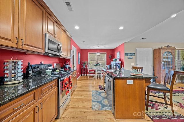 2369 Saratoga Run, Morganton, NC 28655 - kitchen featuring appliances with stainless steel finishes, brown cabinets, a breakfast bar, light wood finished floors, and recessed lighting