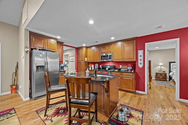 2369 Saratoga Run, Morganton, NC 28655 - kitchen with stainless steel appliances, light wood finished floors, brown cabinets, recessed lighting, and a kitchen island with sink
