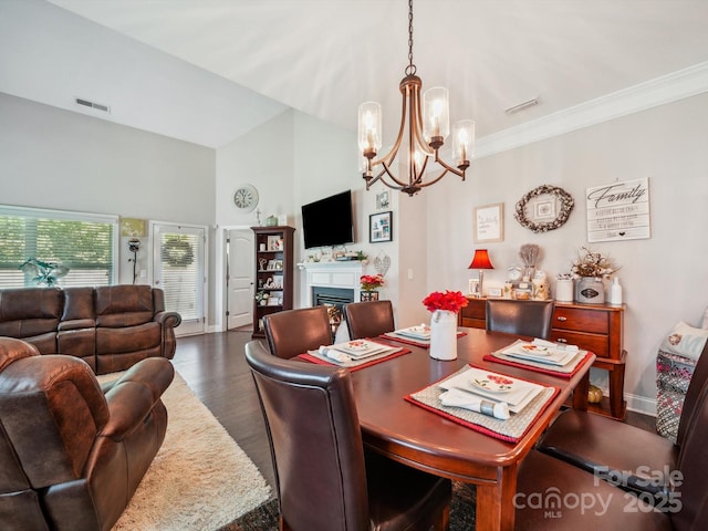 9428 Carneros Creek Rd, Charlotte, NC 28214 - dining area with a chandelier, a glass covered fireplace, dark wood-style flooring, ornamental molding, and a towering ceiling