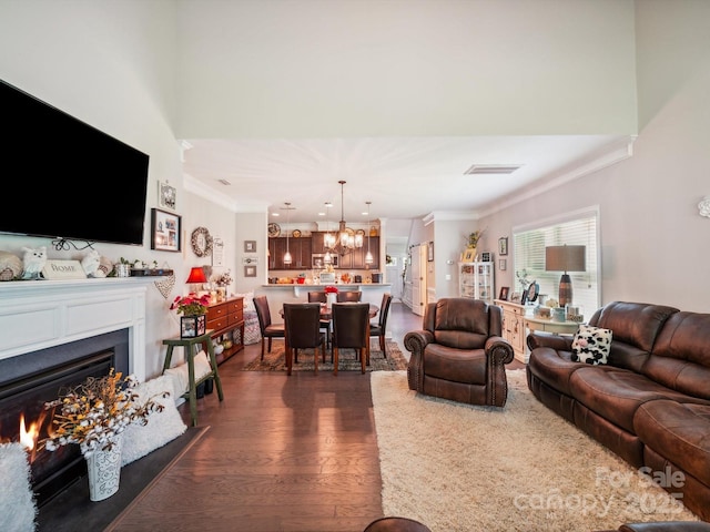 9428 Carneros Creek Rd, Charlotte, NC 28214 - living area with crown molding, a chandelier, dark wood-style flooring, a lit fireplace, and recessed lighting