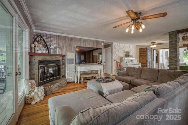665 Will Robbins Ln, Newland, NC 28657 - living room with a textured ceiling, a stone fireplace, a ceiling fan, wood finished floors, and ornamental molding