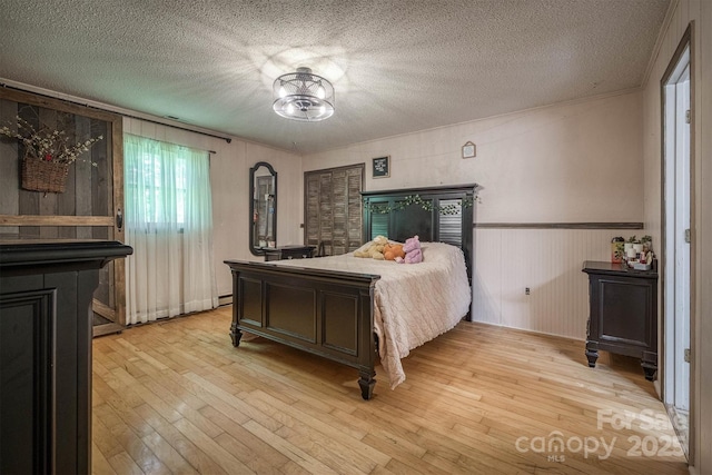 665 Will Robbins Ln, Newland, NC 28657 - bedroom with light wood finished floors, a textured ceiling, and wainscoting