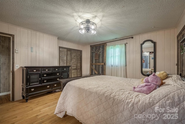 665 Will Robbins Ln, Newland, NC 28657 - bedroom with wood finished floors, arched walkways, a textured ceiling, and wooden walls