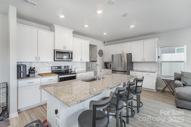 1010 Harry Ct, Albemarle, NC 28001 - kitchen featuring stainless steel appliances, light wood-style flooring, a kitchen breakfast bar, white cabinets, and recessed lighting