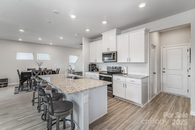 1010 Harry Ct, Albemarle, NC 28001 - kitchen with appliances with stainless steel finishes, light wood finished floors, a kitchen bar, a kitchen island with sink, and recessed lighting