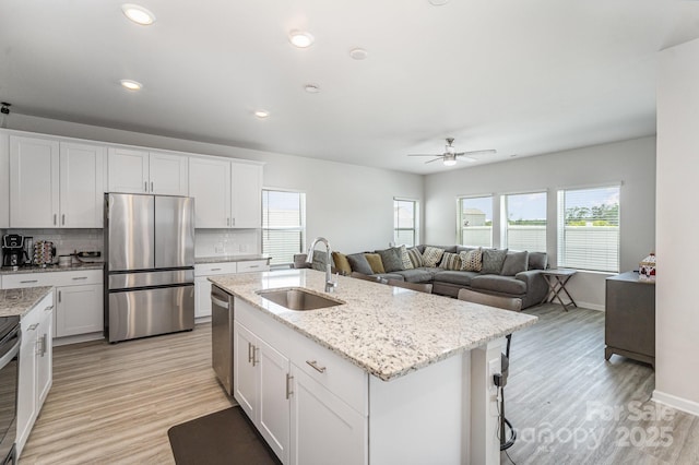 1010 Harry Ct, Albemarle, NC 28001 - kitchen featuring stainless steel appliances, decorative backsplash, a ceiling fan, light wood finished floors, and white cabinets