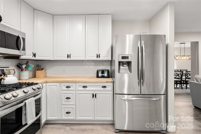 204 Terrys Gap Loop Rd, Fletcher, NC 28732 - kitchen with appliances with stainless steel finishes, butcher block countertops, decorative backsplash, and white cabinets