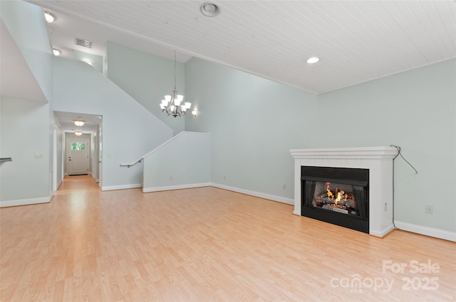 38 Live View Ln, Clyde, NC 28721 - unfurnished living room with wood finished floors, a warm lit fireplace, a chandelier, recessed lighting, and vaulted ceiling