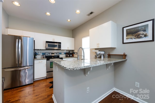 432 W Worthington Ave, Charlotte, NC 28203 - kitchen featuring stainless steel appliances, white cabinets, a peninsula, dark wood-style floors, and recessed lighting