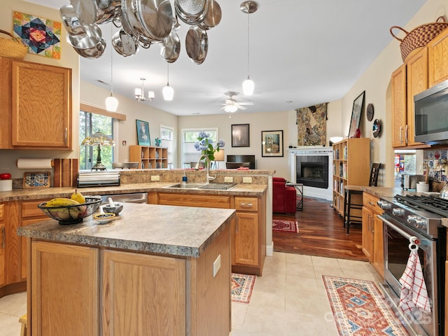 91 Talon Trail Ln, Etowah, NC 28729 - kitchen with stainless steel appliances, a kitchen island, a tiled fireplace, a peninsula, and light tile patterned floors