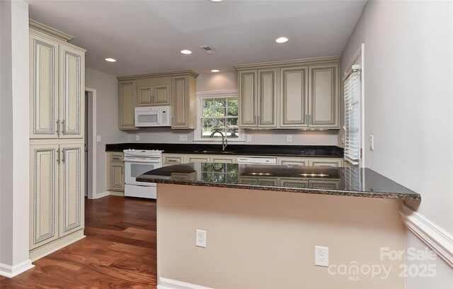2706 Bremer Ct, Charlotte, NC 28210 - kitchen featuring white appliances, cream cabinets, dark wood finished floors, recessed lighting, and dark stone counters