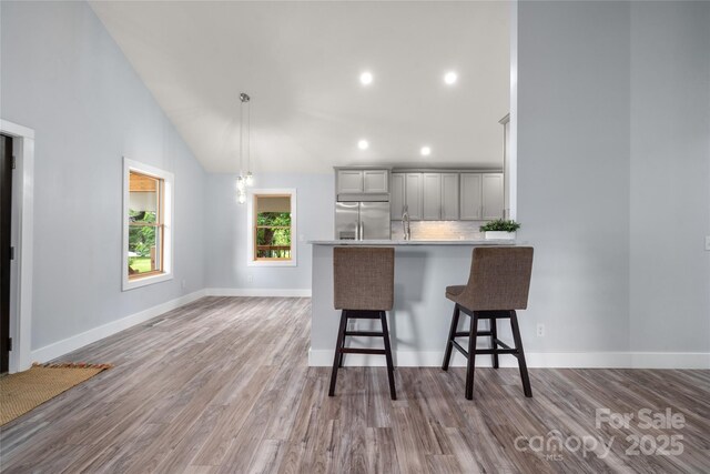 2513 Rolfe St, Hendersonville, NC 28791 - kitchen with stainless steel refrigerator with ice dispenser, a breakfast bar area, backsplash, wood finished floors, and recessed lighting