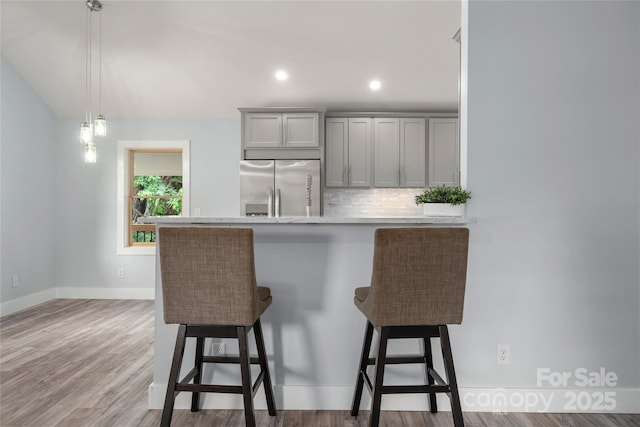 2513 Rolfe St, Hendersonville, NC 28791 - kitchen featuring stainless steel refrigerator with ice dispenser, gray cabinetry, a kitchen bar, light countertops, and decorative backsplash