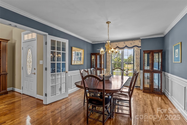 1236 James Farm Rd, Hickory, NC 28602 - dining space with a chandelier, wood finished floors, wainscoting, ornamental molding, and a decorative wall