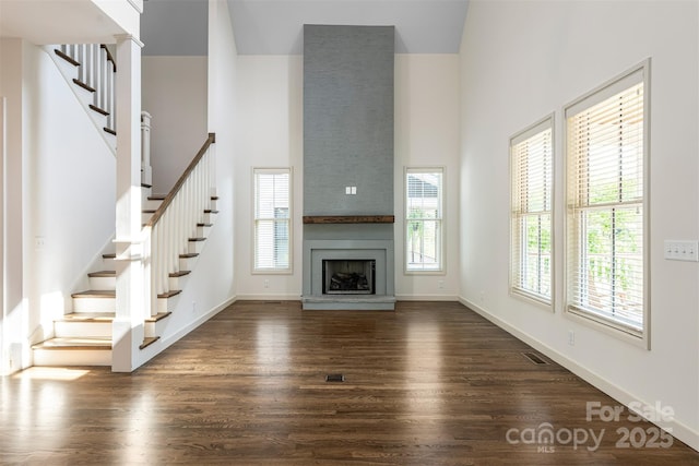 12 Fay Jones Ln, Black Mountain, NC 28711 - unfurnished living room featuring stairs, dark wood-style flooring, a high ceiling, and a fireplace
