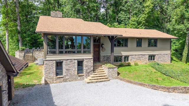2045 Hogback Mountain Rd, Tryon, NC 28782 - view of front of house featuring a chimney, stone siding, a front yard, driveway, and roof with shingles