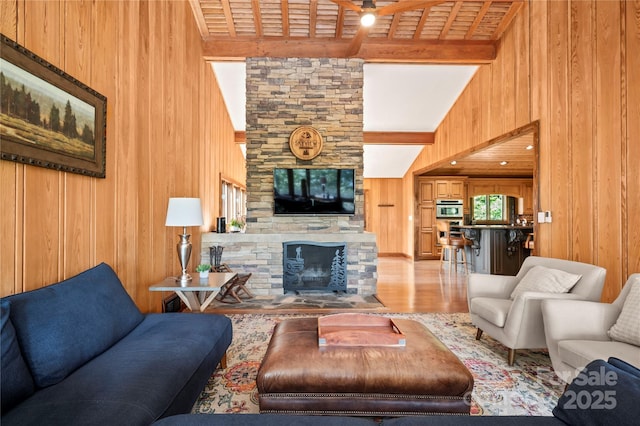 2045 Hogback Mountain Rd, Tryon, NC 28782 - living area featuring wooden walls, beamed ceiling, light wood-type flooring, a stone fireplace, and high vaulted ceiling