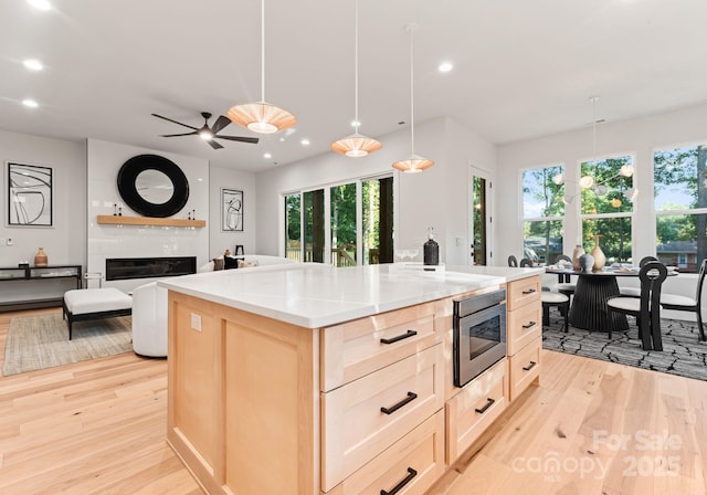 1622 Burtonwood Cir, Charlotte, NC 28212 - kitchen featuring light brown cabinetry, light wood-style flooring, stainless steel microwave, healthy amount of natural light, and recessed lighting