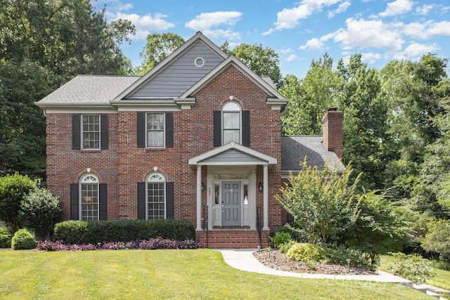 205 Rosedale Ln, Matthews, NC 28105 - view of front of house featuring a front yard, brick siding, a chimney, and a shingled roof