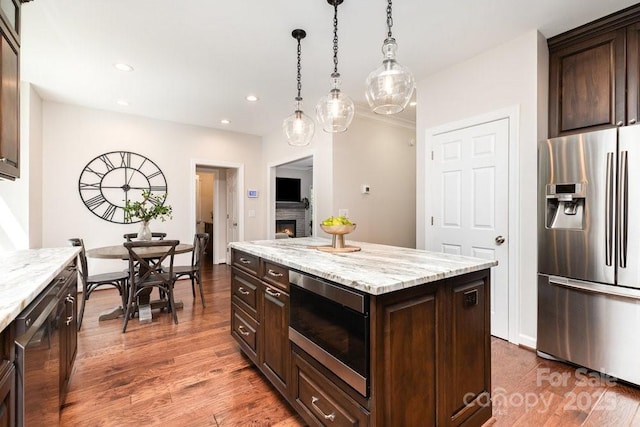 205 Rosedale Ln, Matthews, NC 28105 - kitchen with stainless steel appliances, a warm lit fireplace, dark brown cabinetry, wood finished floors, and recessed lighting
