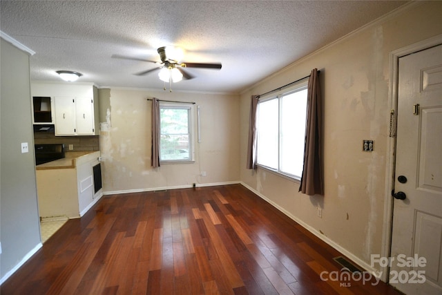 416 E Union St, Marshville, NC 28103 - unfurnished living room featuring dark wood-style flooring, ornamental molding, ceiling fan, and a textured ceiling