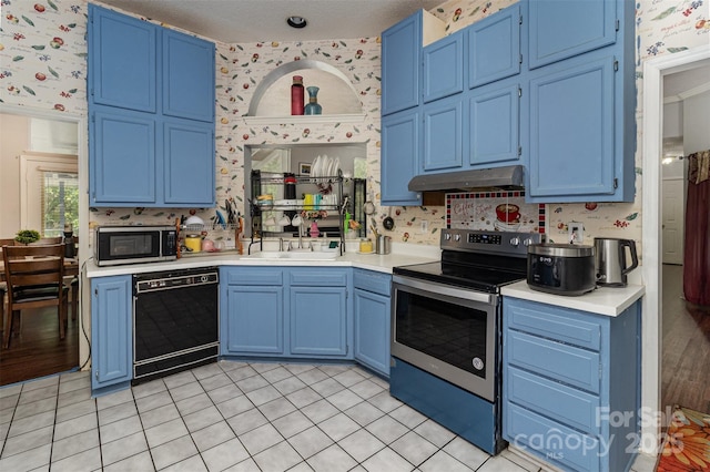 9520 Marshbrooke Rd, Matthews, NC 28105 - kitchen featuring stainless steel appliances, blue cabinetry, wallpapered walls, under cabinet range hood, and light countertops