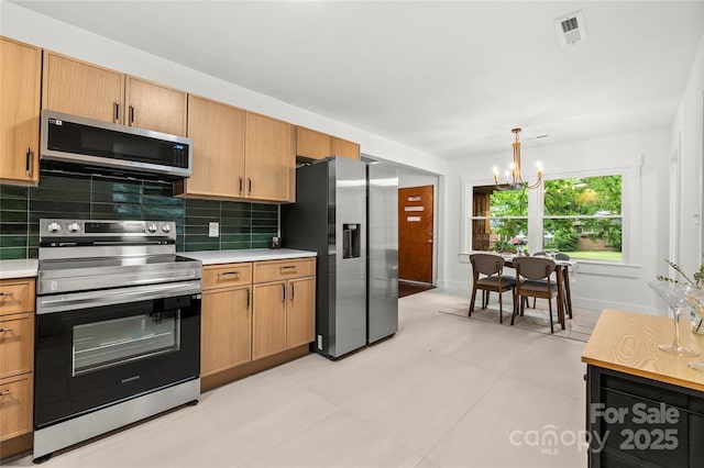 5320 Kildare Dr, Charlotte, NC 28215 - kitchen featuring stainless steel appliances, light countertops, a chandelier, backsplash, and hanging light fixtures