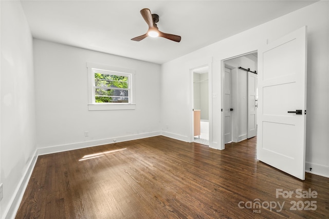 5320 Kildare Dr, Charlotte, NC 28215 - unfurnished bedroom with dark wood finished floors, a barn door, ensuite bath, and a ceiling fan