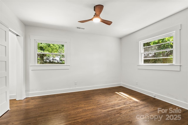 5320 Kildare Dr, Charlotte, NC 28215 - unfurnished bedroom with multiple windows, dark wood-type flooring, ceiling fan, and a closet
