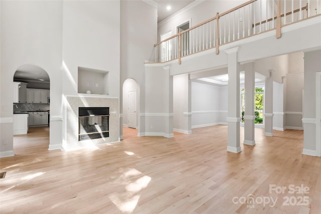 3011 Mckee Rd, Charlotte, NC 28270 - unfurnished living room with a high ceiling, light wood finished floors, a fireplace, crown molding, and arched walkways