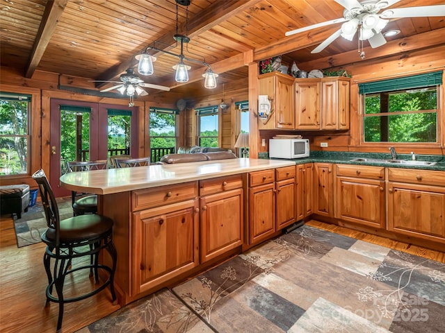 129 Melrose Lake Rd, Saluda, NC 28773 - kitchen featuring a ceiling fan, white microwave, a wood ceiling with exposed beams, a peninsula, and light wood-style flooring