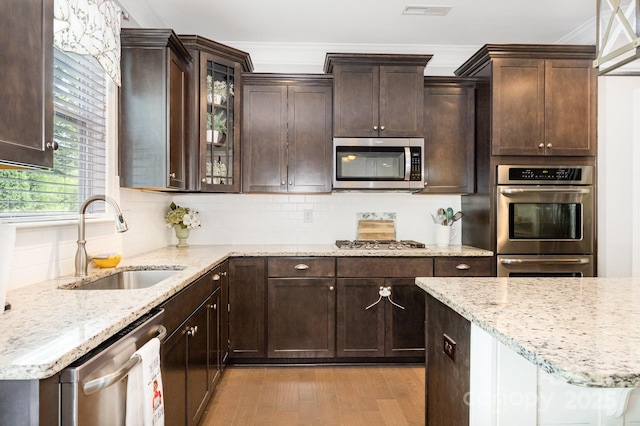 183 Canoe Pole Ln, Mooresville, NC 28117 - kitchen with appliances with stainless steel finishes, light wood finished floors, dark brown cabinets, decorative backsplash, and ornamental molding