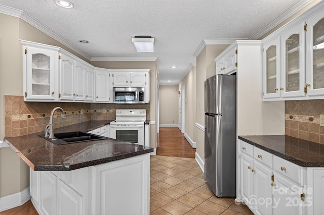 803 Woodmoore Ln, Kannapolis, NC 28081 - kitchen featuring appliances with stainless steel finishes, a peninsula, white cabinets, glass insert cabinets, and a textured ceiling