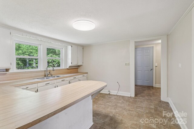 1626 W Park Ave, Albemarle, NC 28001 - kitchen with a textured ceiling, white cabinetry, wooden counters, and crown molding