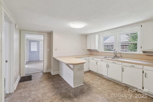 1626 W Park Ave, Albemarle, NC 28001 - kitchen with light countertops, a peninsula, a textured ceiling, and white cabinetry