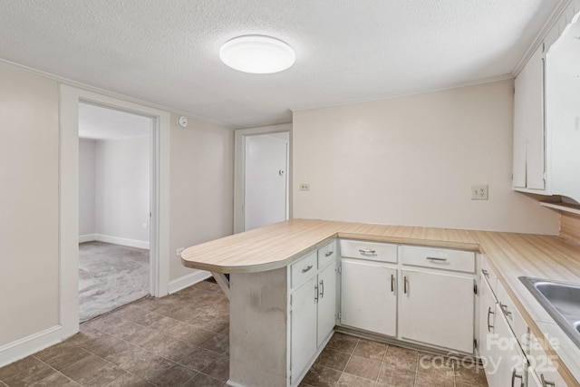 1626 W Park Ave, Albemarle, NC 28001 - kitchen featuring a textured ceiling, a peninsula, light countertops, and white cabinets