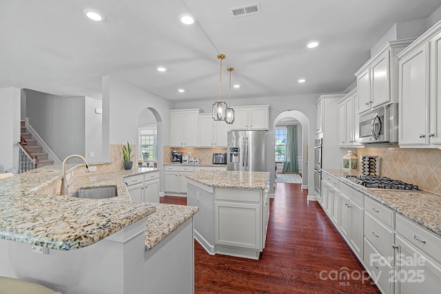 1335 Bryson Gap Dr, Fort Mill, SC 29715 - kitchen featuring arched walkways, appliances with stainless steel finishes, a kitchen island, tasteful backsplash, and recessed lighting
